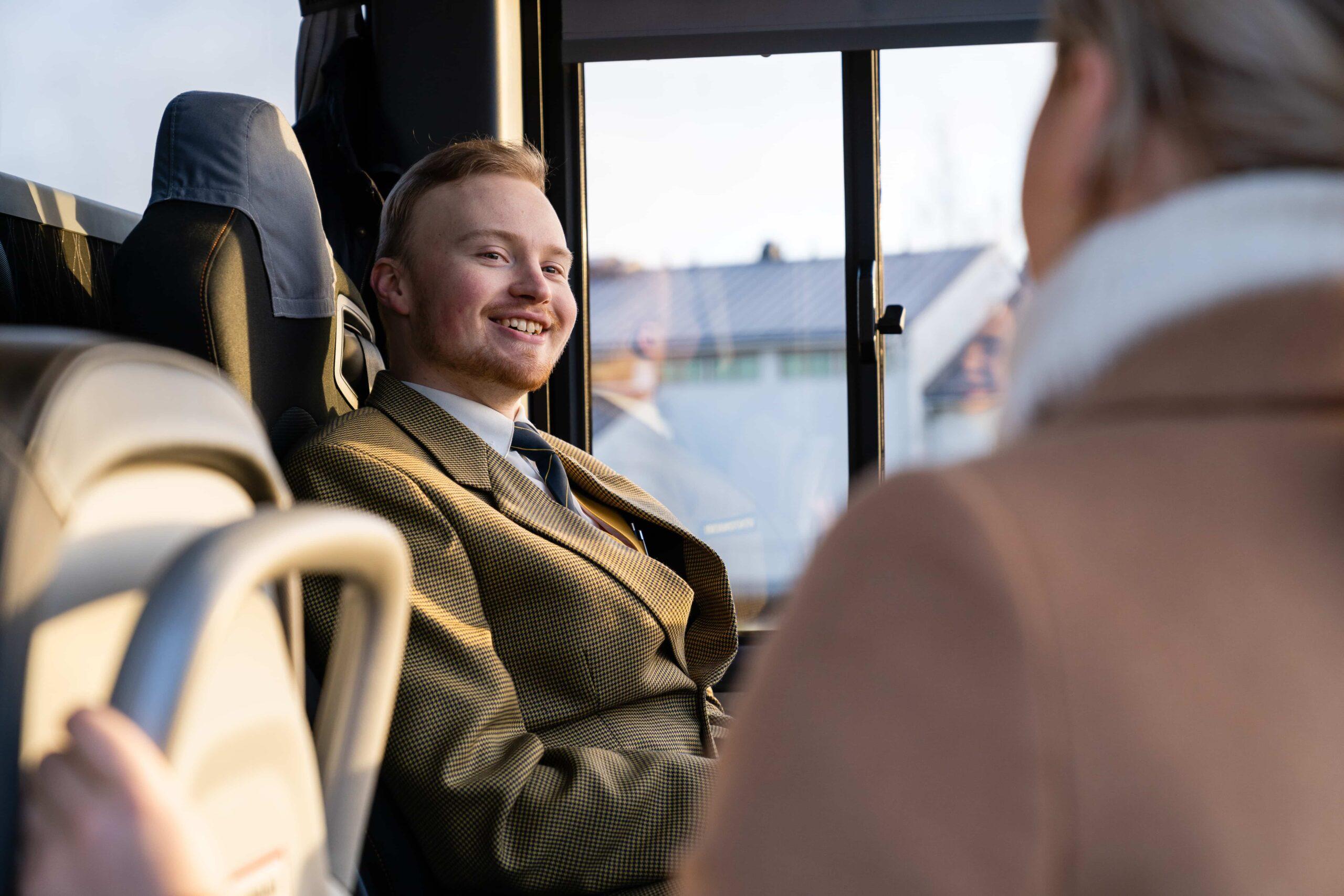 Bussinkuljettaja hymyilee asiakkaalle asiakkaan noustessa bussiin kyytiin.